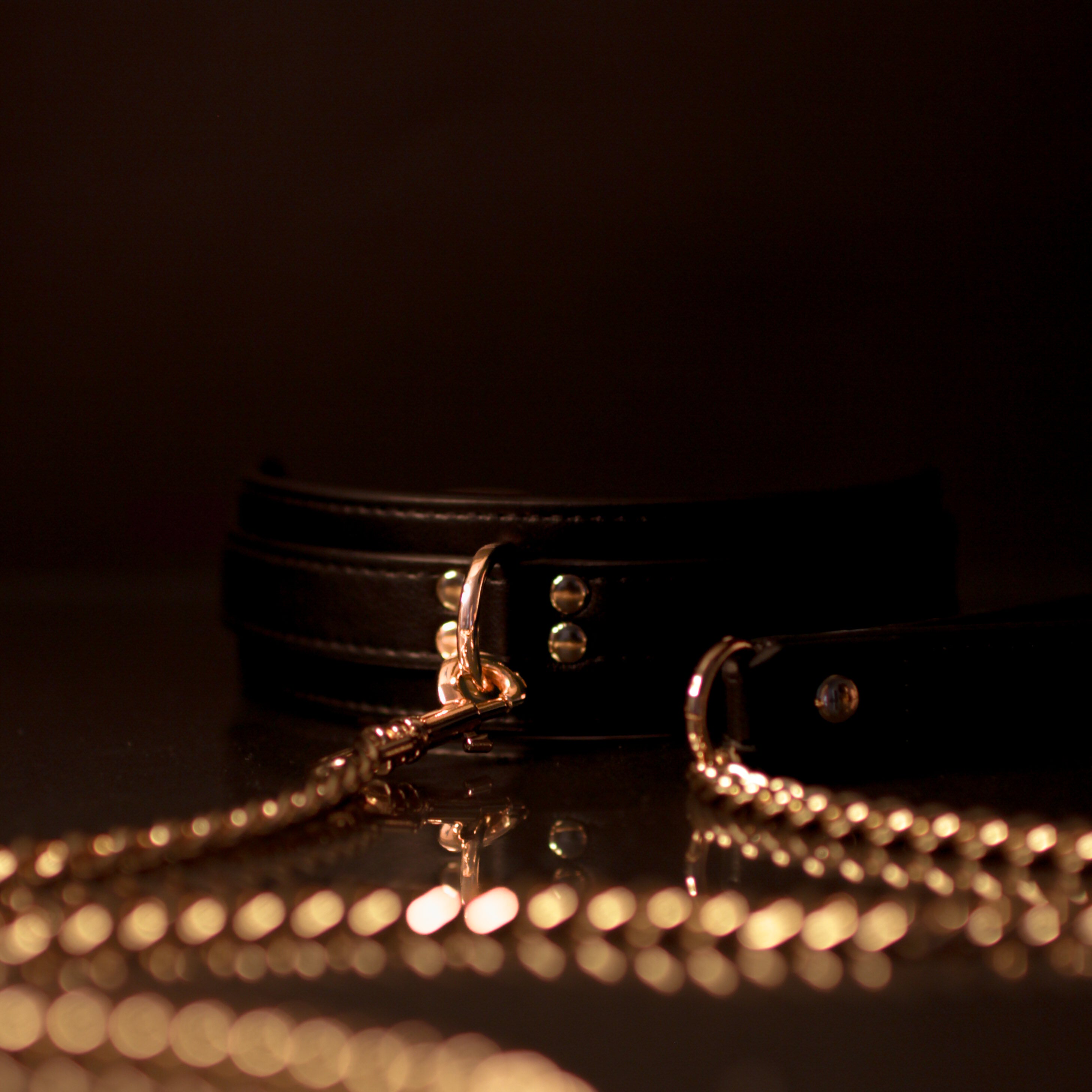 Black neckpiece gold chain and clasp on a dark background