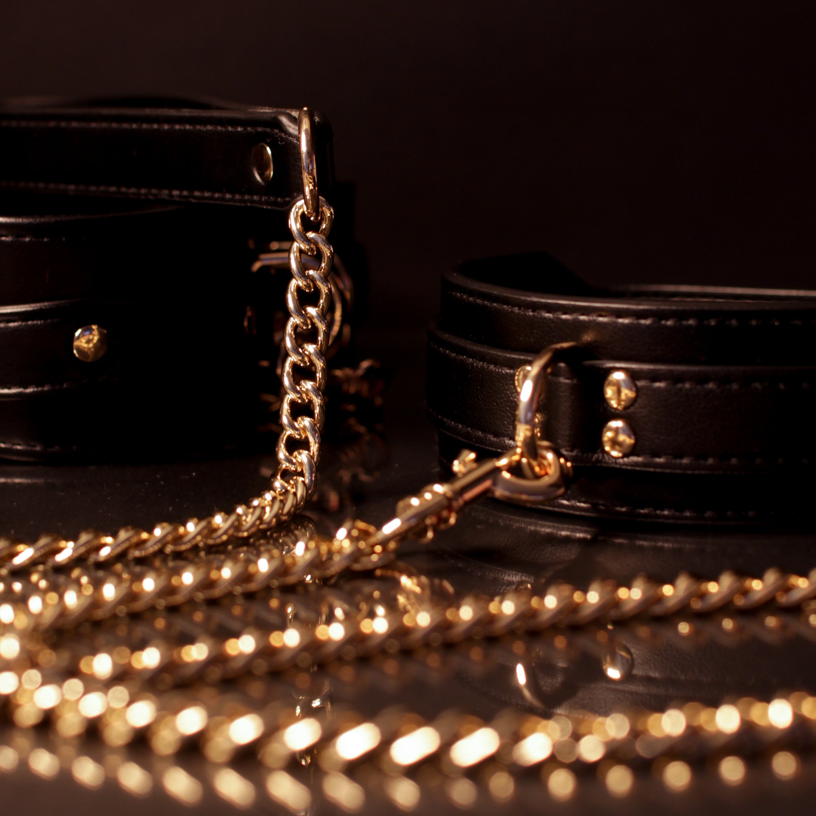 Black neckpiece gold chain and clasp on a dark background