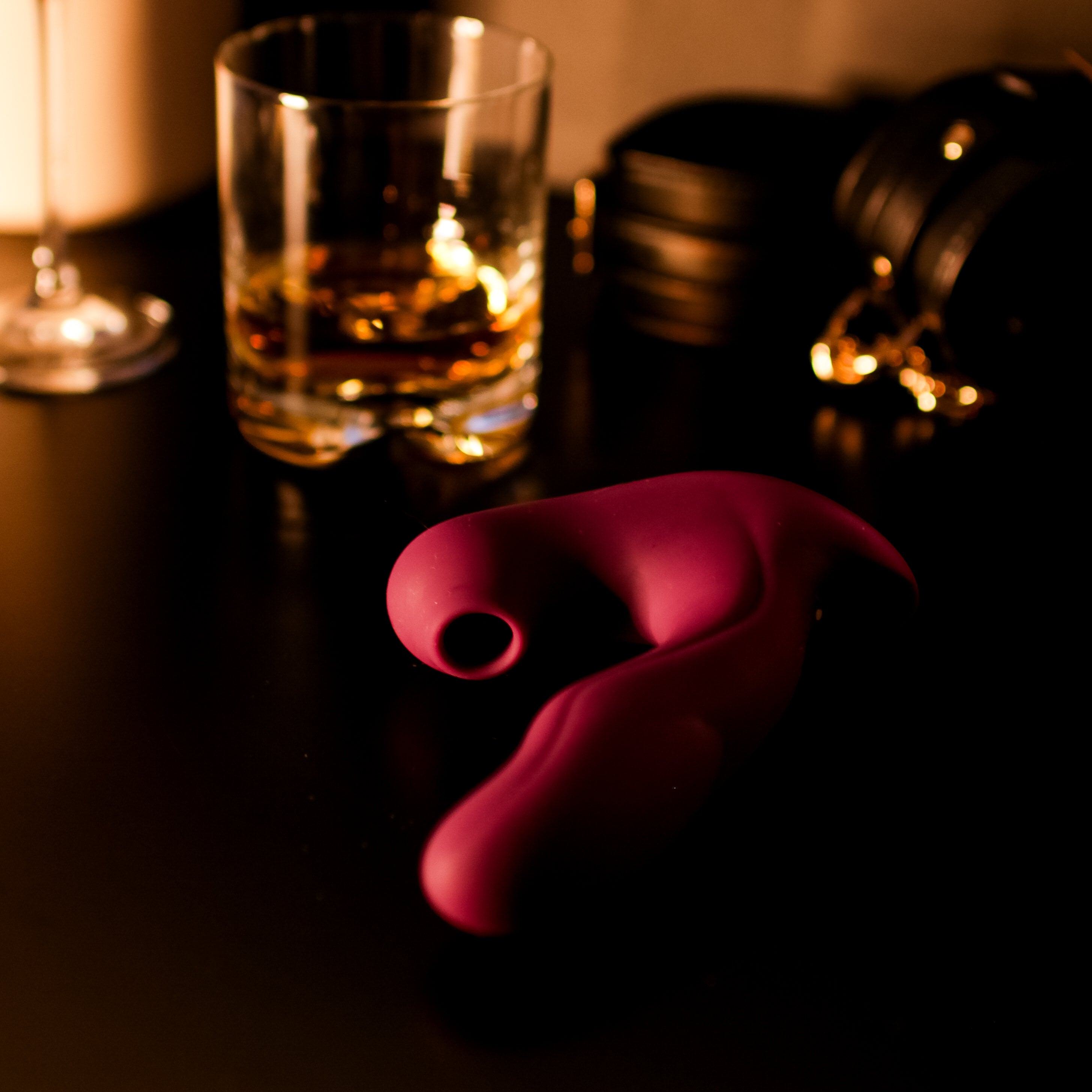 Red pleasure toy on a bedside table in a dim lit room